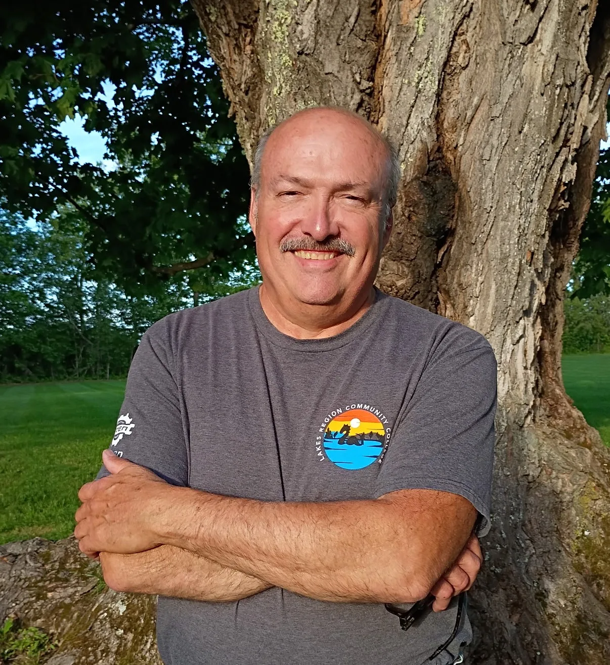 Don Giguere smiling outdoors beside a large tree