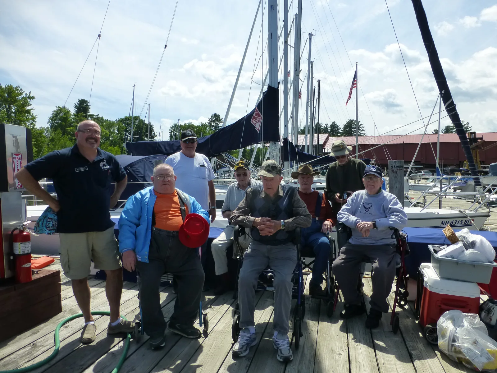 Don Giguere with a group of veterans gathered beside sailboats at a marina